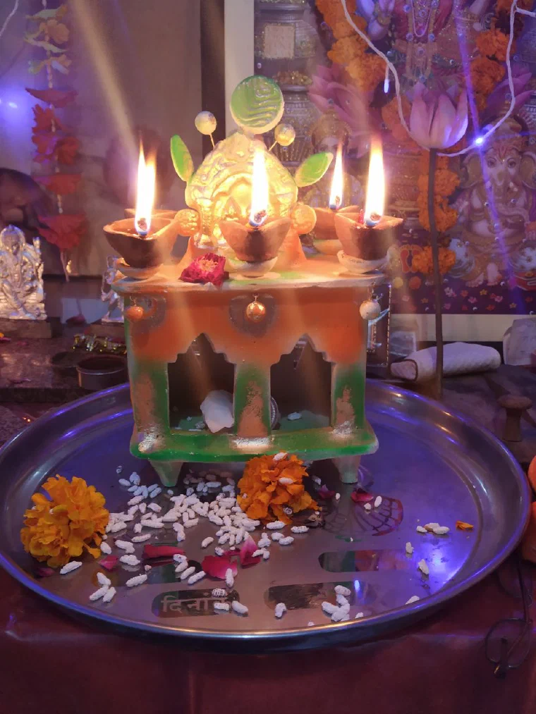 Small clay oil lamps burning before a decorated household shrine during Diwali puja
