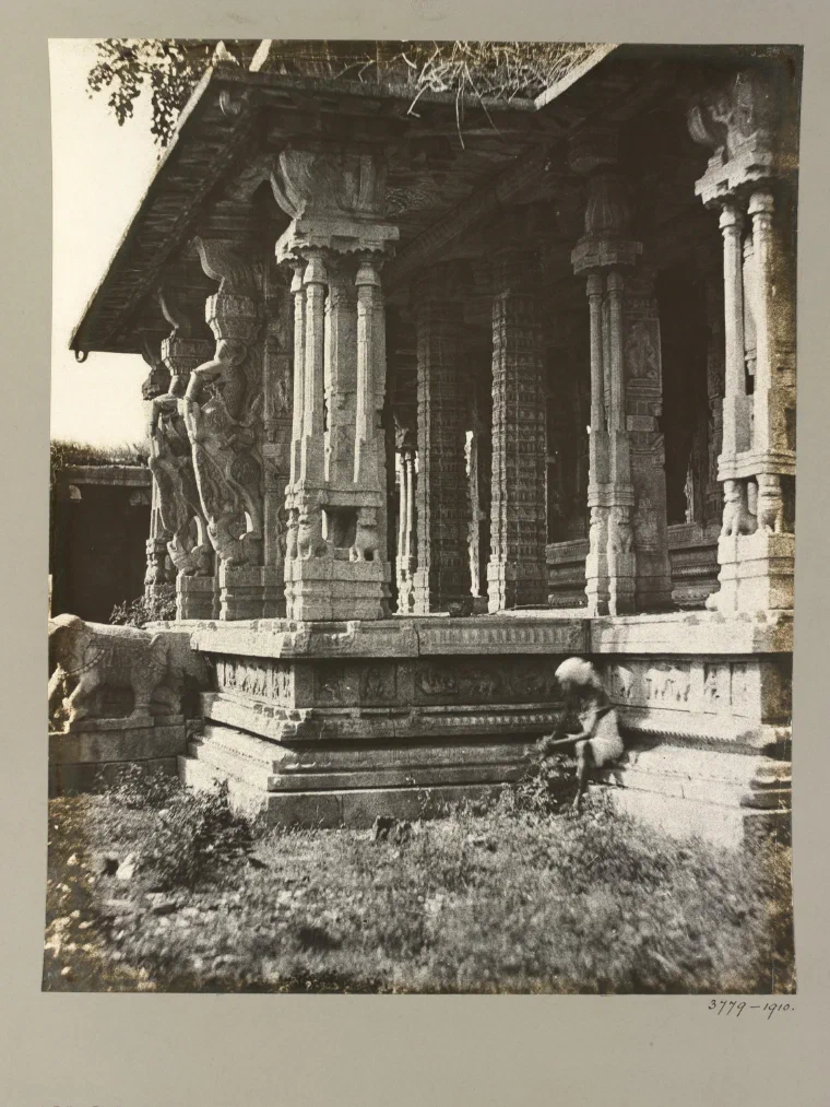 Early photograph from 1856 of a carved stone pavilion at the Vitthala temple complex at Hampi, its pillars intact amid rubble