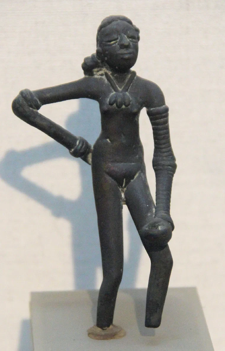 Small bronze figure of a standing young woman with one arm heavy with bangles, hand resting on her hip