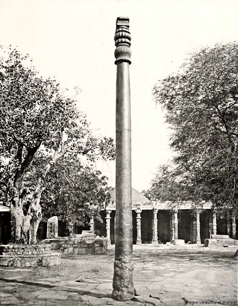 1872 photograph of the iron pillar standing in the courtyard of the Qutb complex, with the arched colonnade behind it