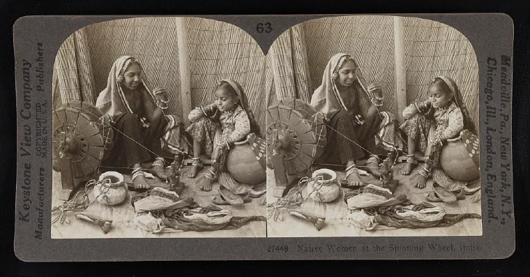 Photograph from around 1928 of Indian women seated at spinning wheels working with cotton thread